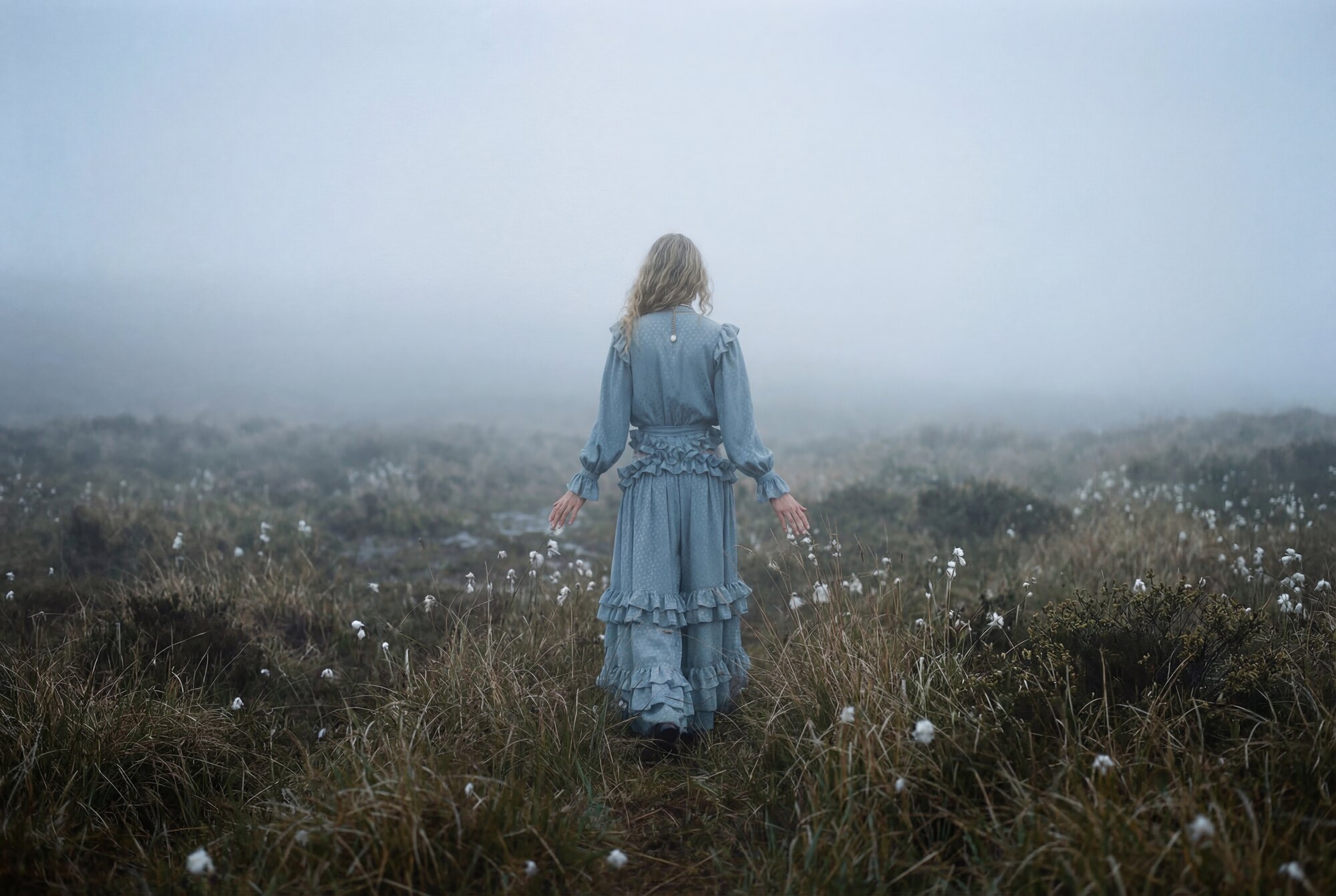 Fashion editorial: a woman in a blue dress walking into fog